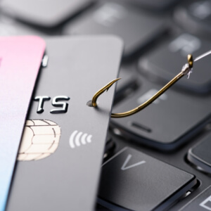 Credit card on fishing hook pulled from stack on keyboard